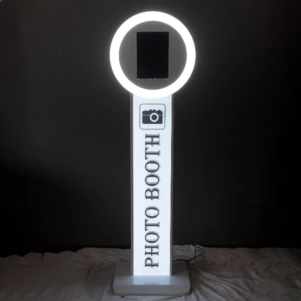 A white digital photo booth stand with a circular light ring and a tablet screen, labeled 'PHOTO BOOTH'.