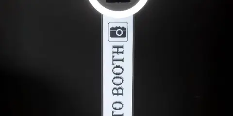 A white digital photo booth stand with a circular light ring and a tablet screen, labeled 'PHOTO BOOTH'.
