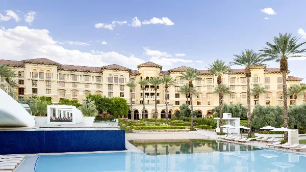 Exterior view of the Green Valley Ranch resort building with a swimming pool and palm trees in the foreground.