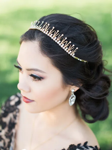 Close-up profile of a bride with an elegant updo, tiara, and professional makeup.