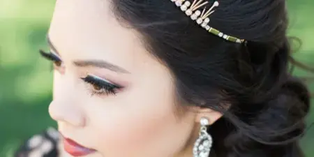 Close-up profile of a bride with an elegant updo, tiara, and professional makeup.
