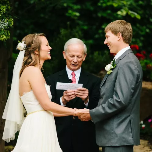 A bride and groom exchanging vows during an outdoor wedding ceremony with an officiant.