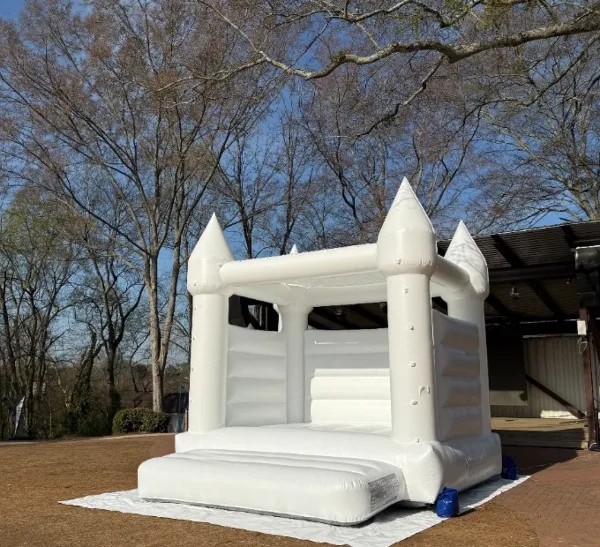 A white castle-themed inflatable bounce house set up outdoors on a lawn.