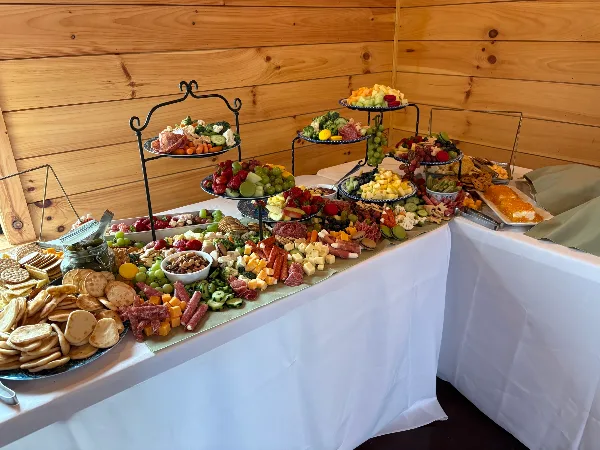A catering buffet table featuring a charcuterie board, fruit platters, and assorted appetizers.