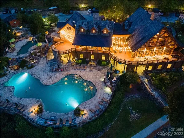 Aerial view of a resort lodge with a swimming pool and outdoor seating area at dusk.