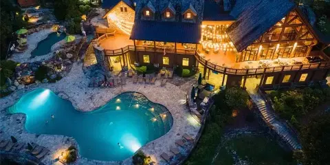 Aerial view of a resort lodge with a swimming pool and outdoor seating area at dusk.