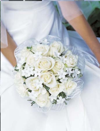 White rose and star jasmine bridal bouquet held by a bride in a white gown