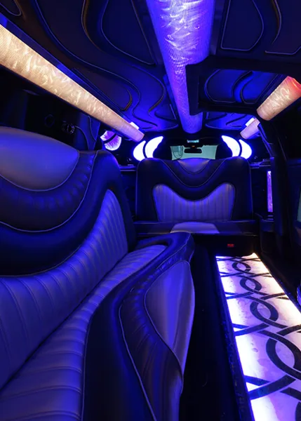 Interior of a luxury limousine or party bus with leather seating and blue LED lighting.