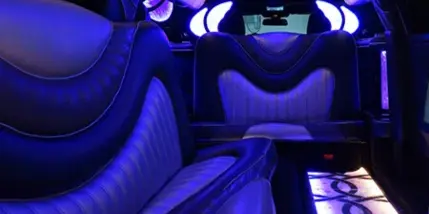 Interior of a luxury limousine or party bus with leather seating and blue LED lighting.