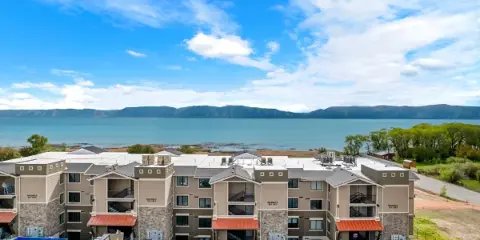 Aerial view of the Water's Edge Resort condominium buildings situated directly on the shore of Bear Lake with mountains in the background.