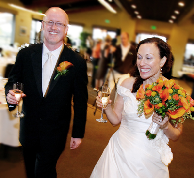 A smiling bride and groom holding champagne flutes at a wedding reception.
