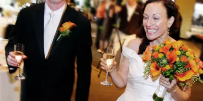 A smiling bride and groom holding champagne flutes at a wedding reception.
