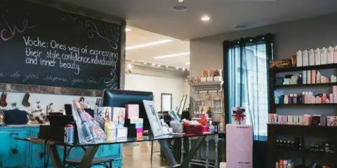 Interior view of Salon Voche showing a retail display table, product shelves, and a chalkboard sign.