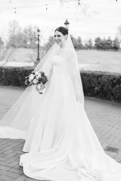 Bride in a white wedding dress and veil holding a bouquet outdoors