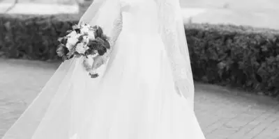 Bride in a white wedding dress and veil holding a bouquet outdoors