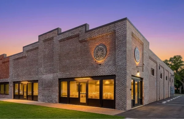 Exterior view of the Culinary Productions brick venue building at dusk with illuminated windows showing the interior event space.