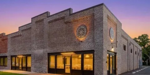 Exterior view of the Culinary Productions brick venue building at dusk with illuminated windows showing the interior event space.