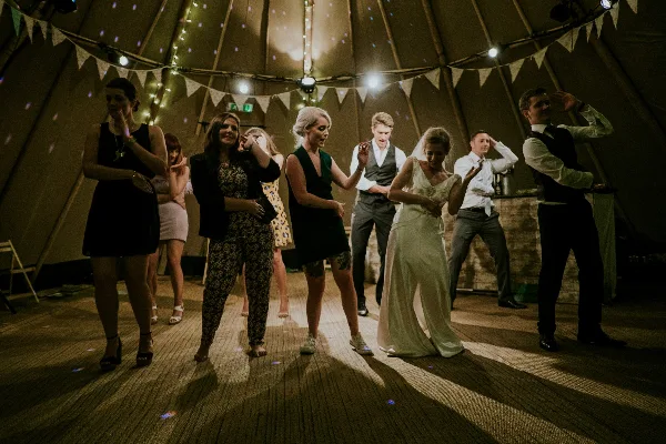 Guests dancing at a wedding reception in a tented venue.