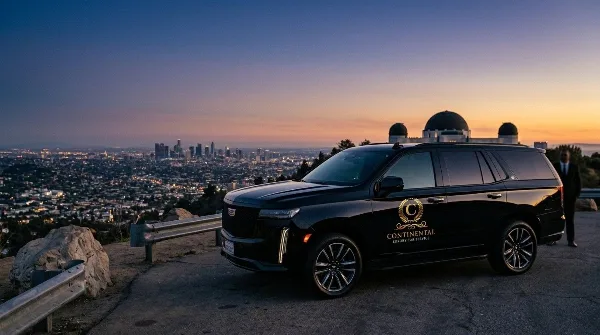 Black Cadillac Escalade ESV with Continental Luxury Car Service logo parked at a Los Angeles overlook with a chauffeur standing nearby