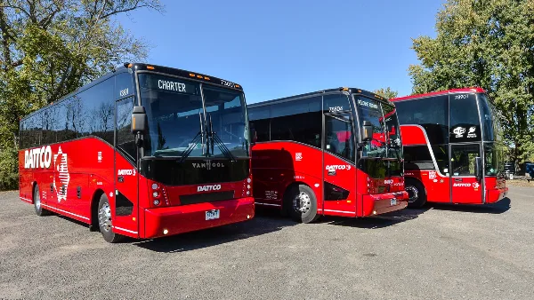 Three red DATTCO motorcoaches parked in a row outdoors.