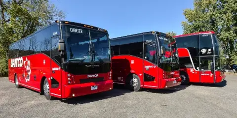 Three red DATTCO motorcoaches parked in a row outdoors.