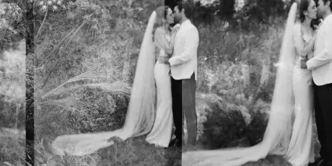 Black and white photograph of a bride and groom kissing in a garden setting.