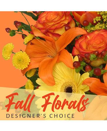 A close-up of a fall floral arrangement with orange lilies, yellow chrysanthemums, and roses, labeled 'Fall Florals Designer's Choice'.