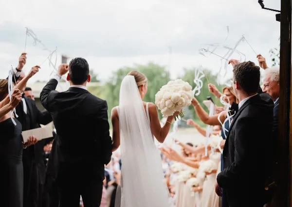 Bride holding a large white floral bouquet during a wedding ceremony.
