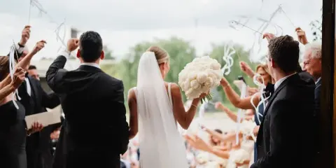 Bride holding a large white floral bouquet during a wedding ceremony.
