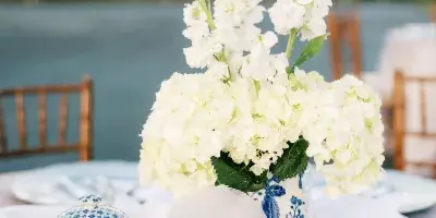 Outdoor wedding table setting with white floral centerpiece and table number 15, overlooking a lake.