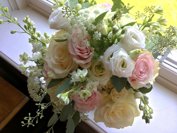 A wedding bouquet composed of white and pink roses with greenery accents.