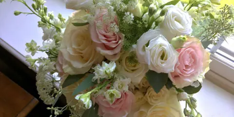 A wedding bouquet composed of white and pink roses with greenery accents.