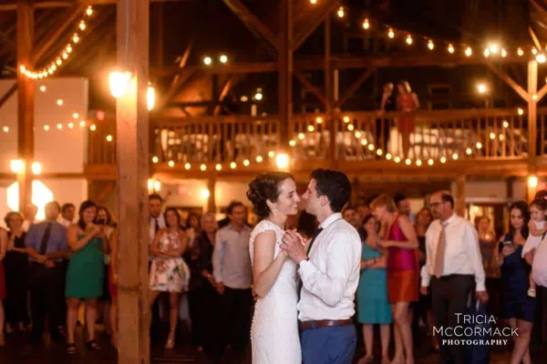A bride and groom slow dancing at a wedding reception while guests watch.