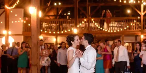 A bride and groom slow dancing at a wedding reception while guests watch.