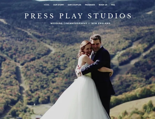 A bride and groom embracing in a wedding dress and suit against a backdrop of rolling green hills.