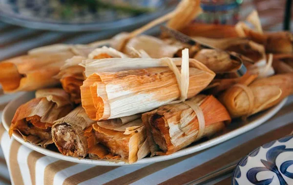A plate of tamales wrapped in corn husks, representing the regional cuisine offered by Con Amor Catering & Events.