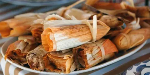 A plate of tamales wrapped in corn husks, representing the regional cuisine offered by Con Amor Catering & Events.