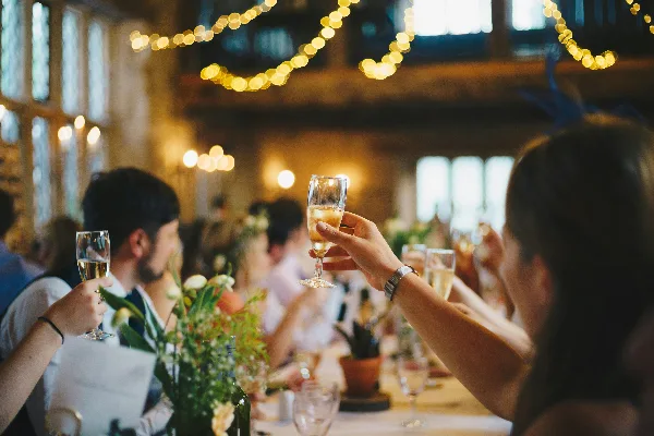 Guests at a wedding reception table raising champagne glasses in a toast.