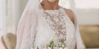 Bride with styled updo, makeup, veil, and floral bouquet