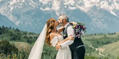 Bride and groom kissing in a field with the Grand Teton mountains in the background
