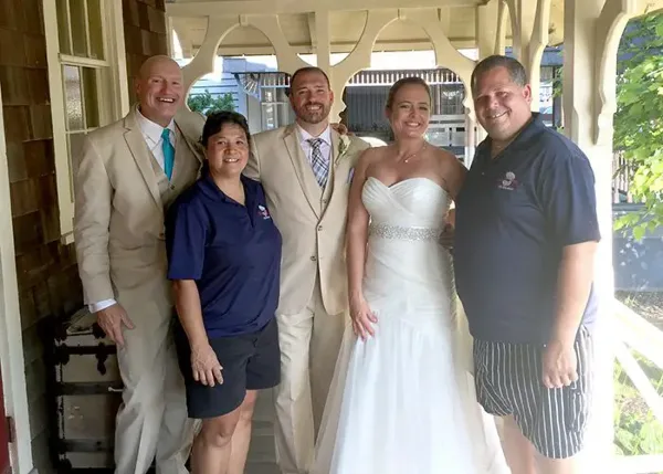 A group photo of the DRJ Catering staff posing with a bride and groom at a wedding event.