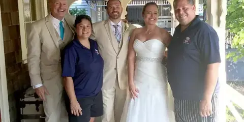 A group photo of the DRJ Catering staff posing with a bride and groom at a wedding event.