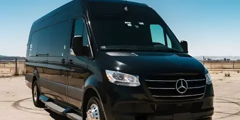 A black Mercedes-Benz Sprinter van parked in an open paved area.