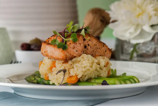 A plated meal featuring seared salmon, rice, and asparagus garnished with microgreens.