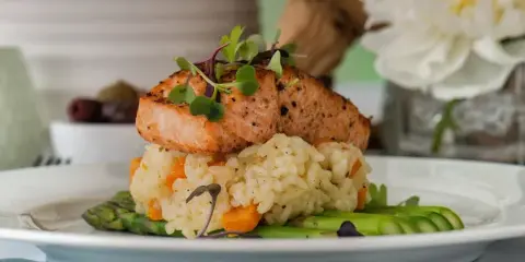 A plated meal featuring seared salmon, rice, and asparagus garnished with microgreens.