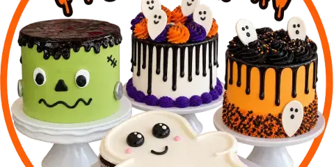 A display of Halloween-themed cakes and cupcakes, including a Frankenstein cake and ghost-shaped cupcakes.