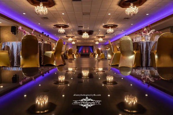 Interior of an elegant banquet hall with a dance floor, chandeliers, and decorated tables.