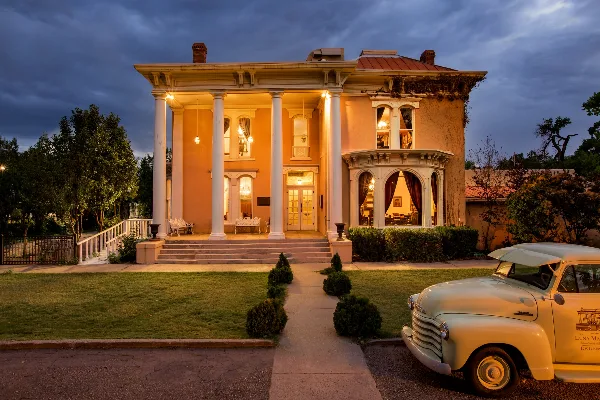 Exterior view of The Luna Mansion event venue at dusk, featuring a white columned porch and manicured lawn.