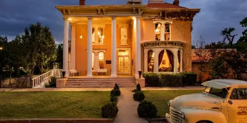 Exterior view of The Luna Mansion event venue at dusk, featuring a white columned porch and manicured lawn.