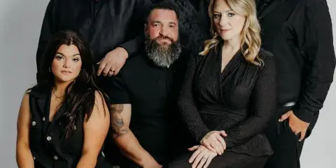 A professional group portrait of the Crossroads Entertainment team, consisting of six individuals in black formal wear.